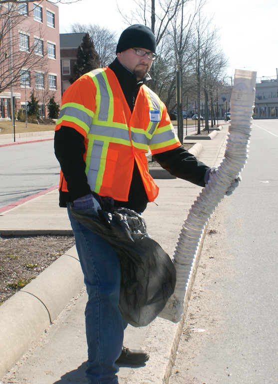 CLEANUP DAY: Adam Miner, a member of the Humanists of RI, picks up a dryer vent hose that was left on Park Avenue in front of Cranston High School East.