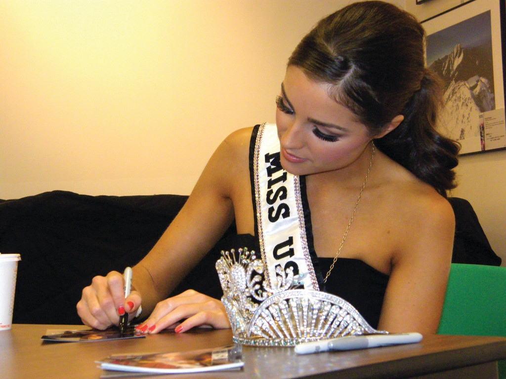 WITH HER CROWN: Miss USA signs autographs for youngsters at the Cranston Public Library.