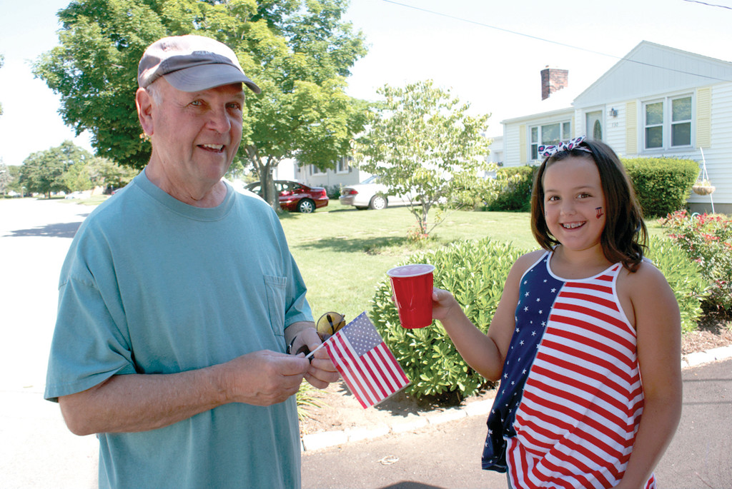 CUSTOMER SATISFACTION: Olivia VanPatten hands a cup of lemonade to her neighbor, the Rev. Francis O’Hara, a retired priest from St. Kevin’s Church who stopped by to support the cause.