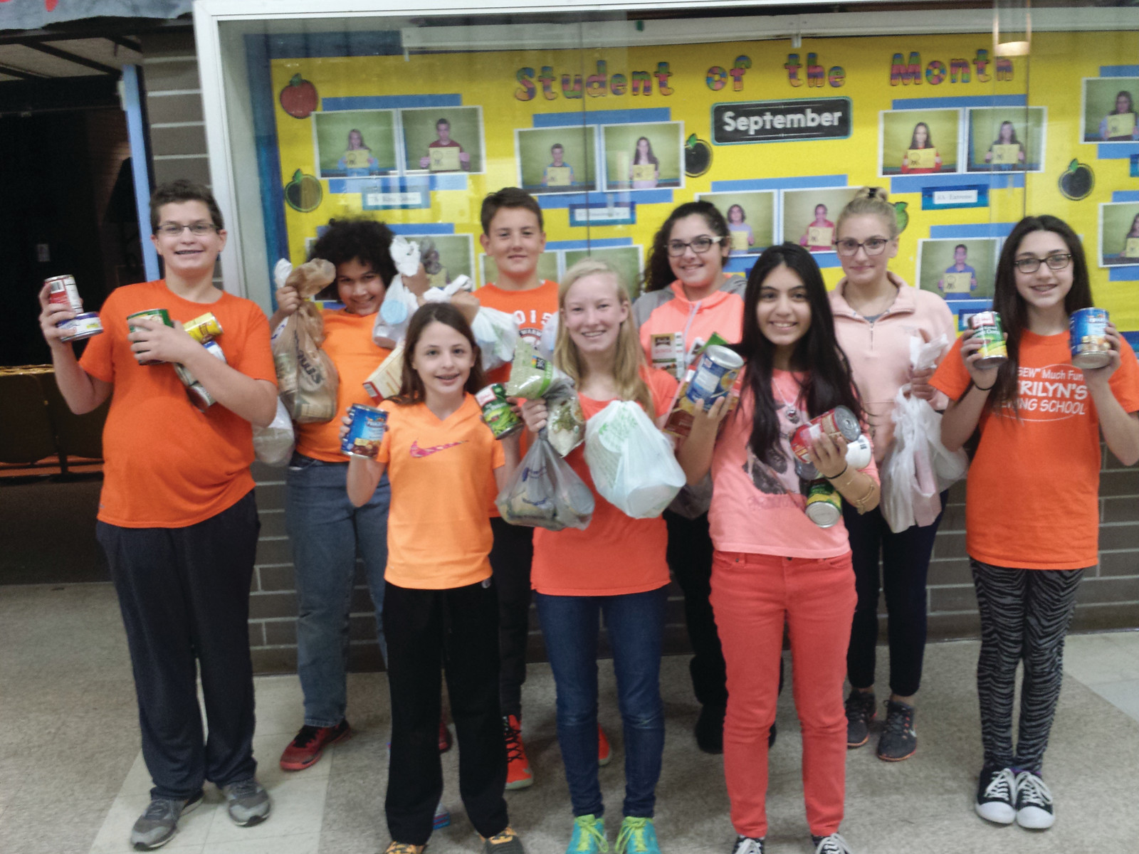AN ORIGINAL FOUNDER: Elizabeth Cowart, one of the three original founders of the Cranston “Go Orange” event, poses with several of her peers at Western Hills Middle School as they show just some of the hundreds of non-perishable food items collected in this year’s drive, which began on Oct. 28. The student council at Western Hills also asked students to bring canned goods to the first school dance on Oct. 30.