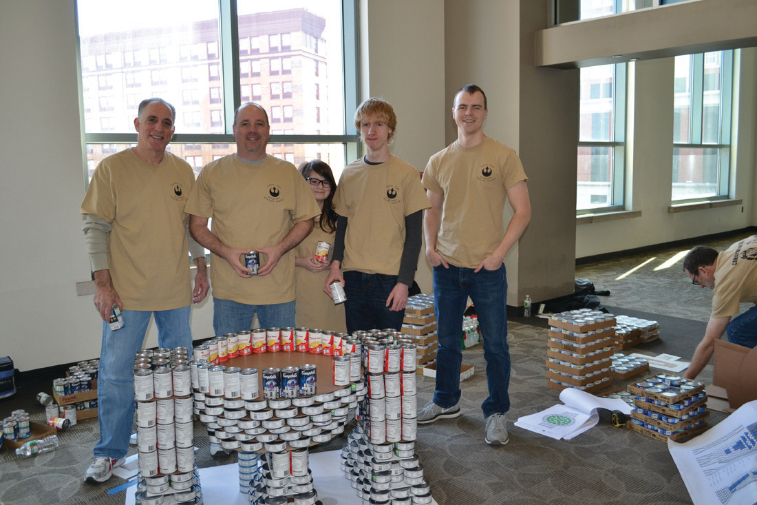 CRANSTON RESIDENTS were among those building the Saccoccio-DiPrete Engineering-H.V. Collins team’s sculpture, which won the Best Meal award in the recent Canstruction RI event to benefit the RI Community Food Bank. Working on the R2-D2 part of their sculpture are, from left, Steve Guglielmo, a principal of Cranston-based Saccoccio Architects; Ron Stevenson with his children, Kate and Cole; and Jakob Cruikshank.