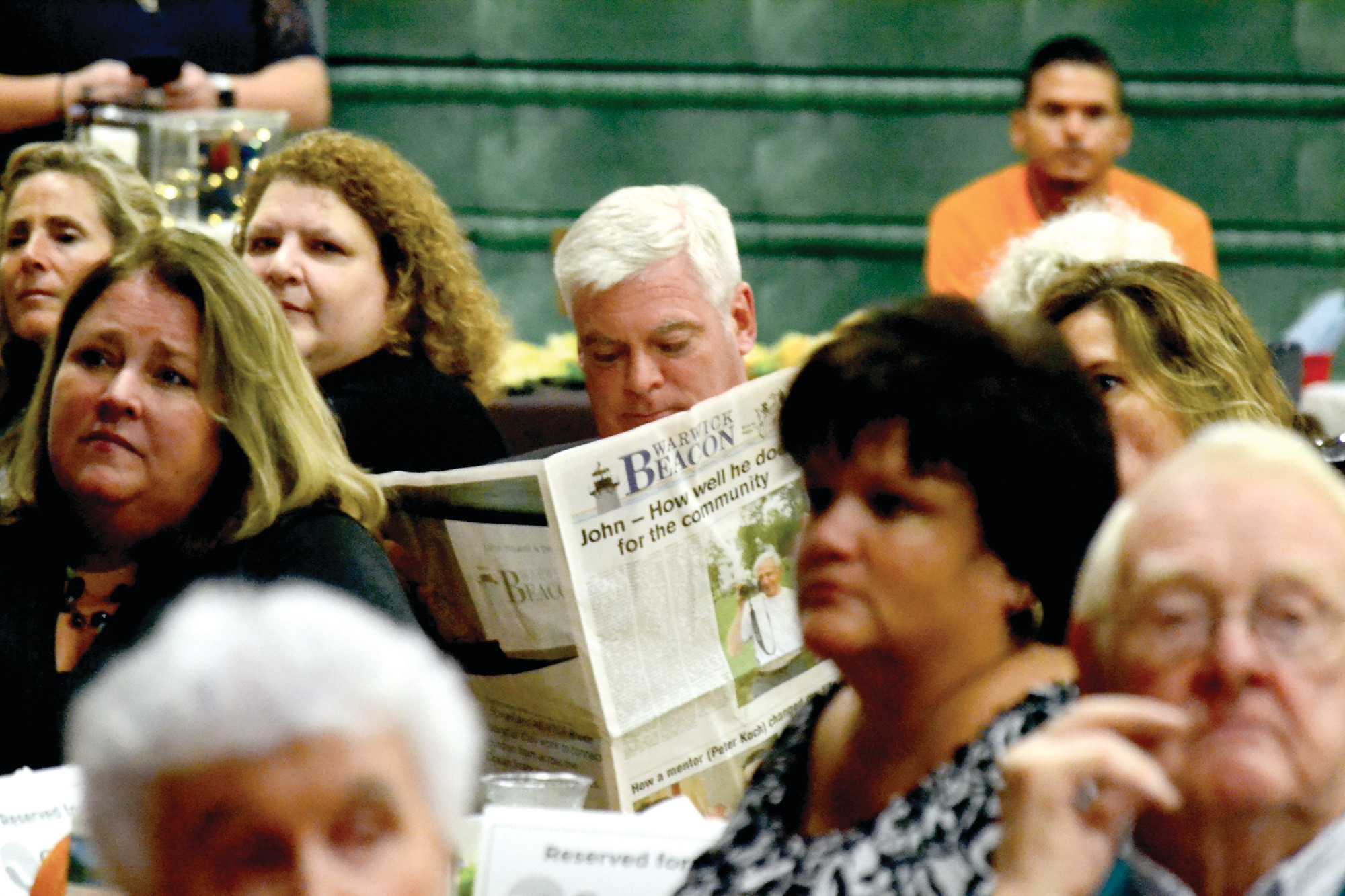 EXTRA EXTRA: Mayor Avedisian sits absorbed in the special edition of the Beacon that was produced especially for John Howell’s tribute event, held at Bishop Hendricken last Thursday evening.