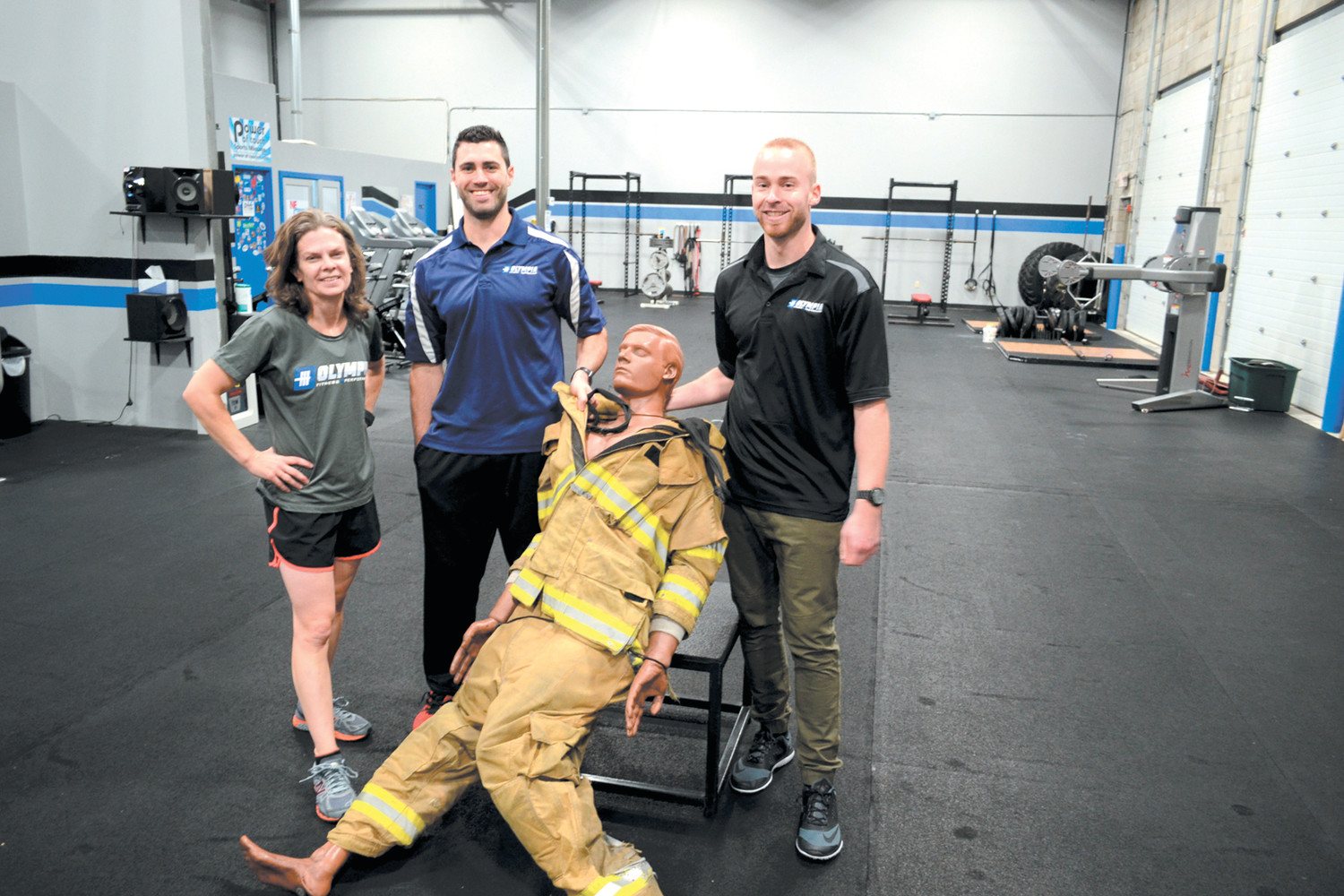 TRAINING FOR DUMMIES: Maura J. Zimmer (NSCA), Olympia Fitness owner Steve Zarriello (CSCS, TPI certified) and Mike Lefebvre pose with their workout dummy, which helps prepare potential firefighter recruits for the final stage of the PPA physical fitness examination.