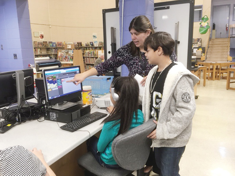 COACHING EM UP: Edgewood Elementary school librarian Kather Tanner shows the 5th graders the newest Minecraft coding challenge.