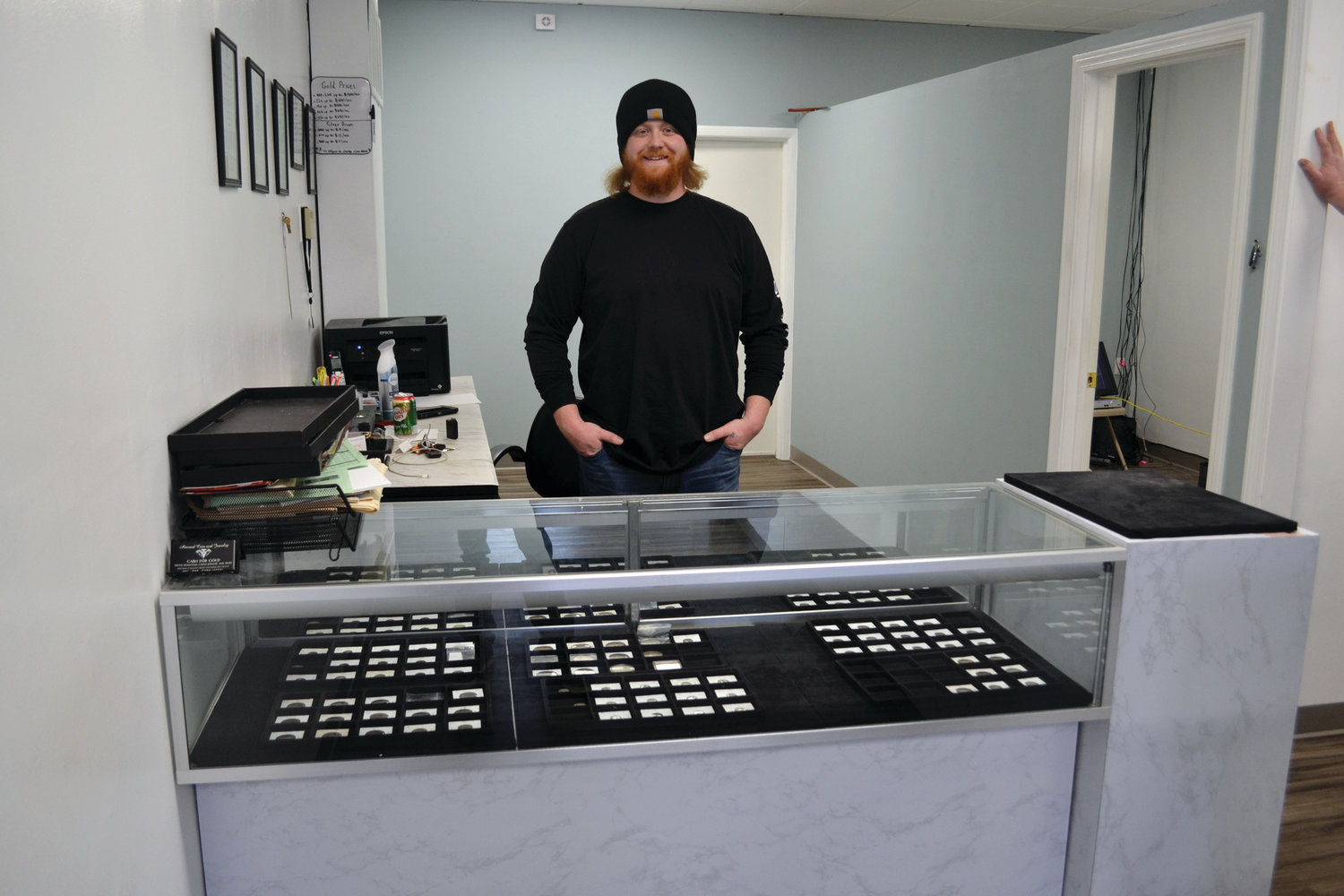 CASE AND POINT: Atwood Coin & Jewelry owner Gilbert Mendoza stands behind a case inside the business at 1450 Atwood Ave. in Johnston. Ed Helgran said if young people are looking for a hobby, they should get into collecting coins because of the potential payoff down the line.