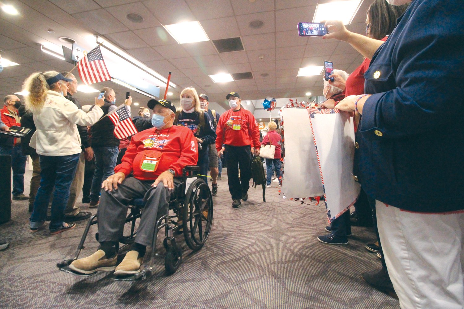 THEIR SERVICE ACKNOWLEDGED: Veterans arrive at the airport to cheers waving flags and the music of the
fifes and drums.