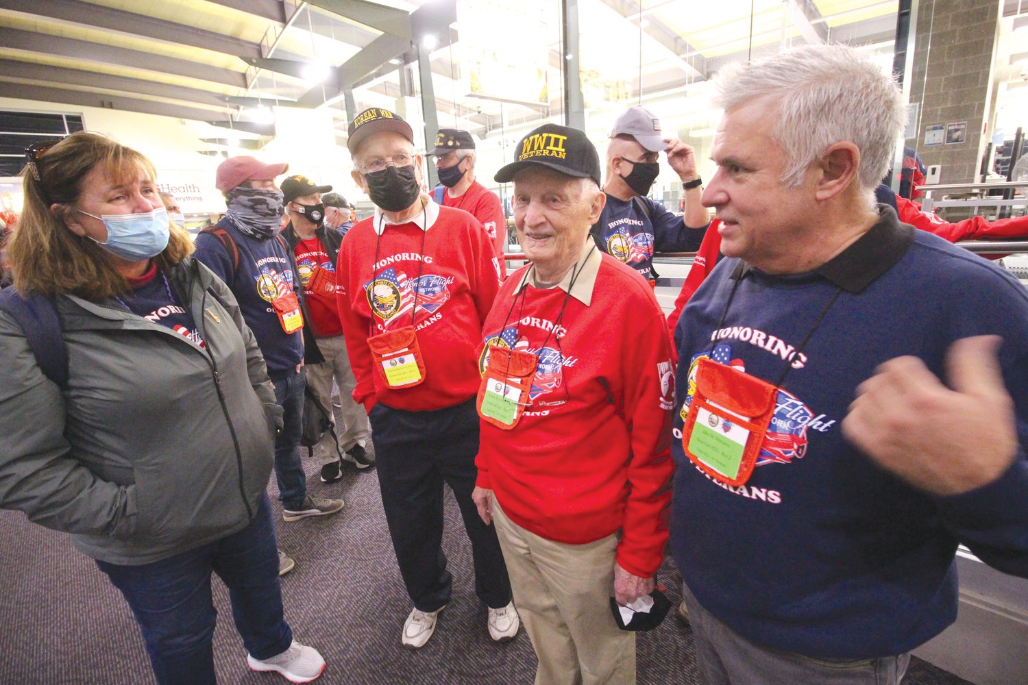 SON SERVES AS GUARDIAN: Guardian Nancy Perda, left, Navy veteran Thomas McGee III ; WWII veteran John Romano and his son John chat before marching to the departure gate. John served as his father’s guardian.