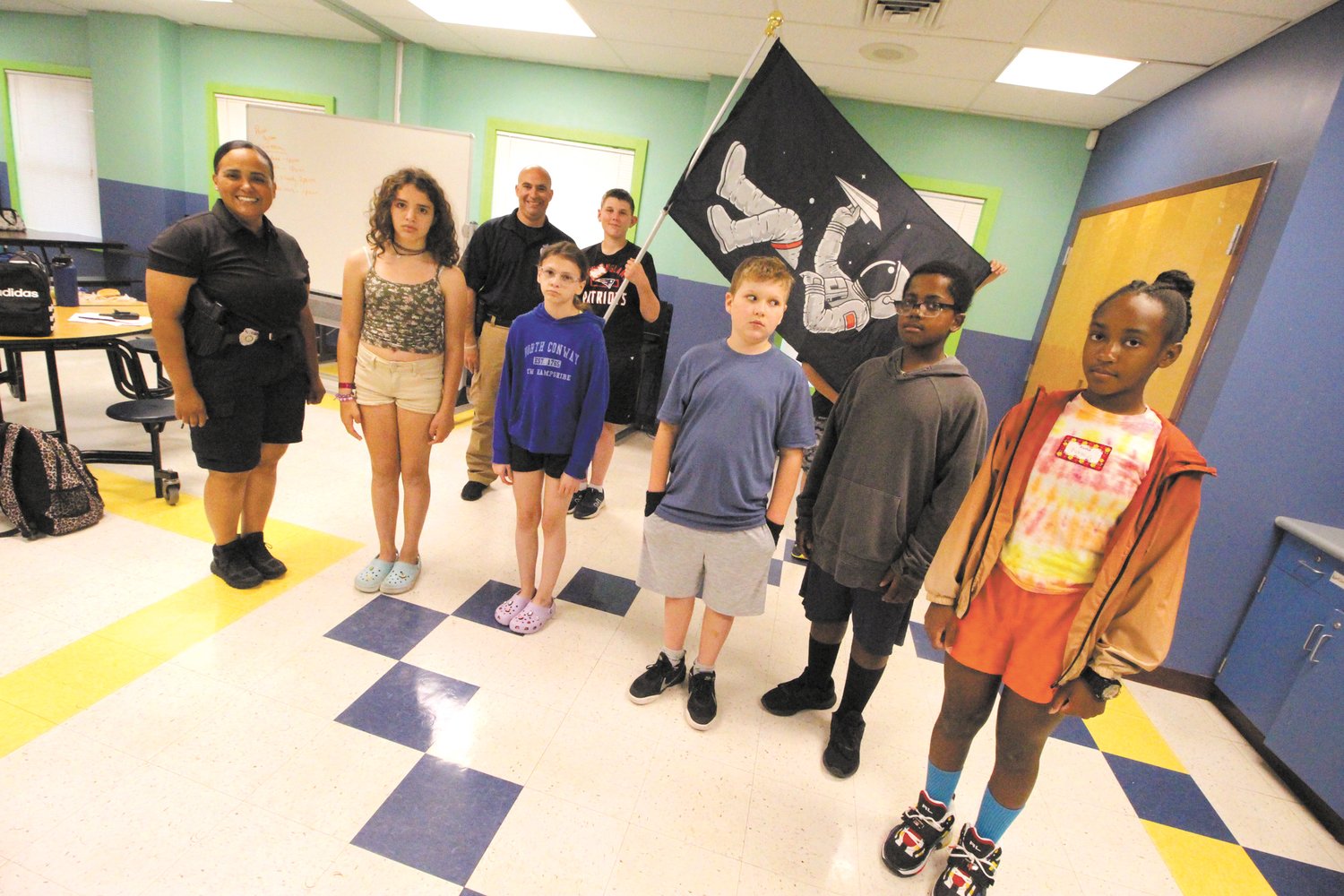 THEIR FLAG: Campers in the Warwick Police Department Leadership Camp that started Monday at the Oakland Beach branch of the Warwick Boys and Girls Clubs chose an outer space banner under which to gather as they will be “exploring” new opportunities. School resource officers Rose Michel and Al Marano are running this session of the camp. (Warwick Beacon photo)