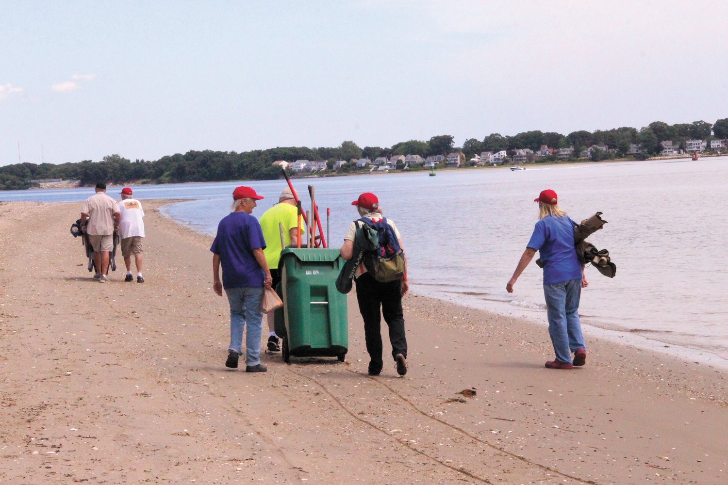 GOOD THING IT WAS LOW TIDE: Volunteers carrying a tent, tables, chairs and equipment walk toward Gaspee Point on Friday.