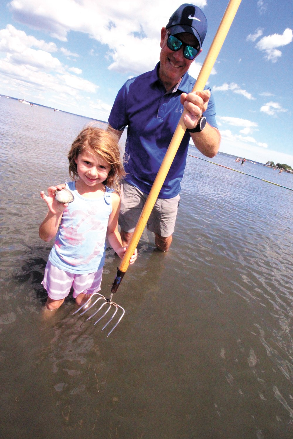 A KEEPER: Adlee Malouin , 6, holds up one of the quahogs she dug up during the program held at North Kingstown Town Beach Saturday. With her is Jim Halley 
