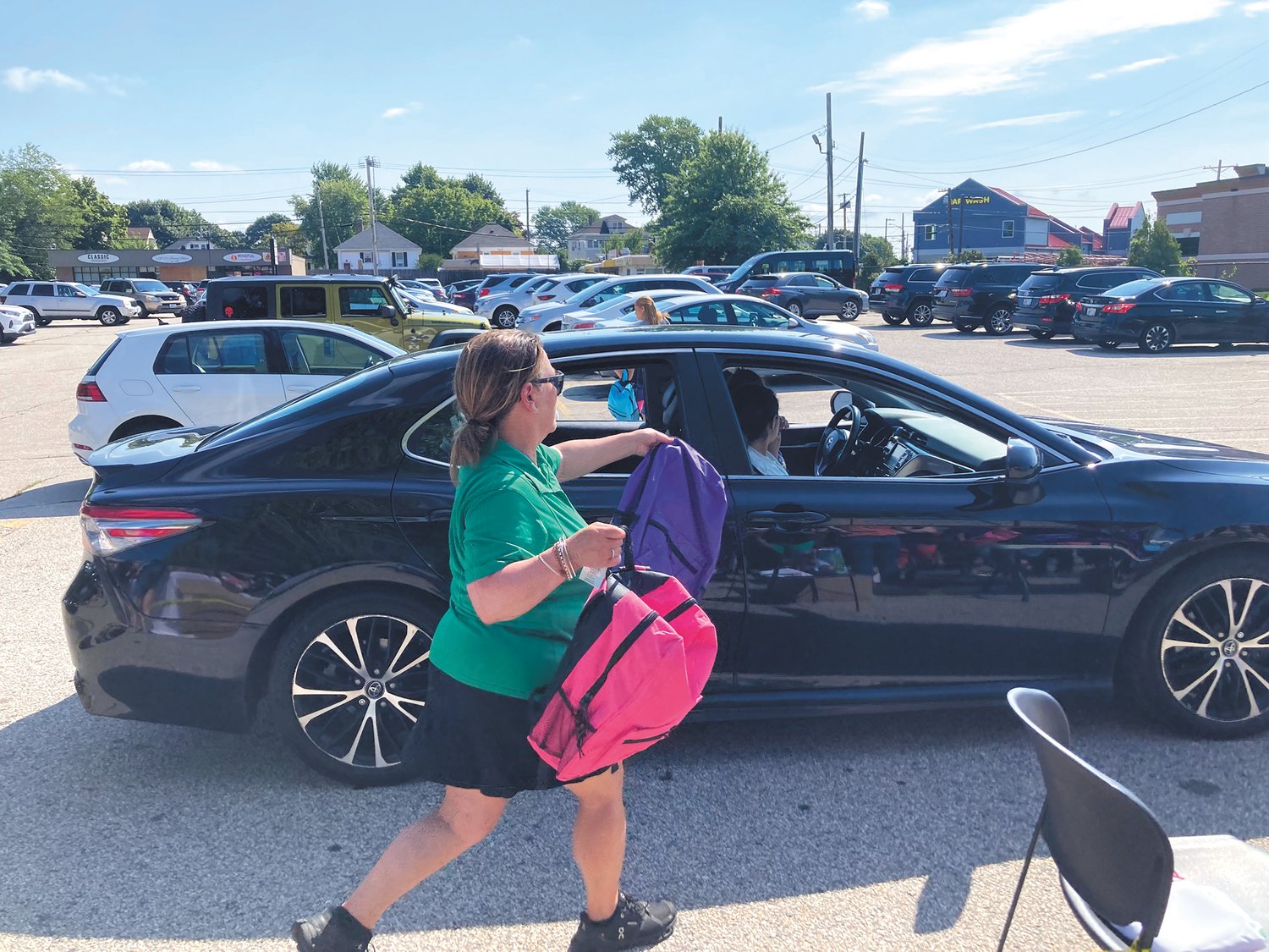 KEEP THE LINE GOING: With a long line of cars, volunteers hastily gathered backpacks and handed them over to families Saturday morning. (Herald photo)