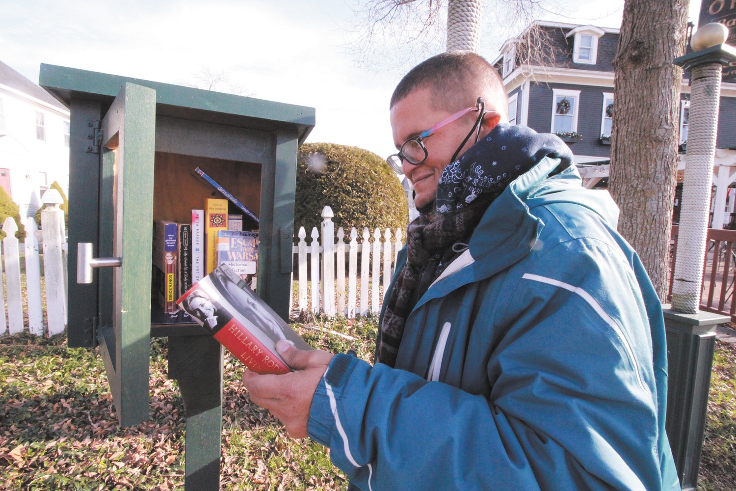 ON HIS READING LIST: Angelo Nieves was delighted to find a book on Hillary Clinton in one of several book exchange box libraries in the village.