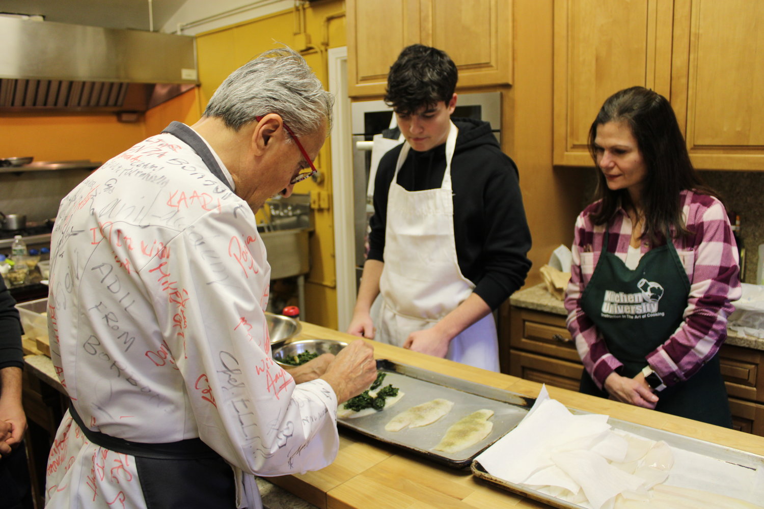 STUFF YOUR SOLE: Chef Walter demonstrates to Mike and Dee Schena how to properly add a spinach filling to the fish the class is preparing.  