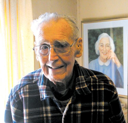 FOLLOWING HIS PASSION:  Soon to be 101 years old, Ray Finelli continues to do portraits although  not as fast as he would like to.  He is pictured in his living room (studio) with the portrait he painted of his wife, Edith, behind him. (Cranston Herald photo)