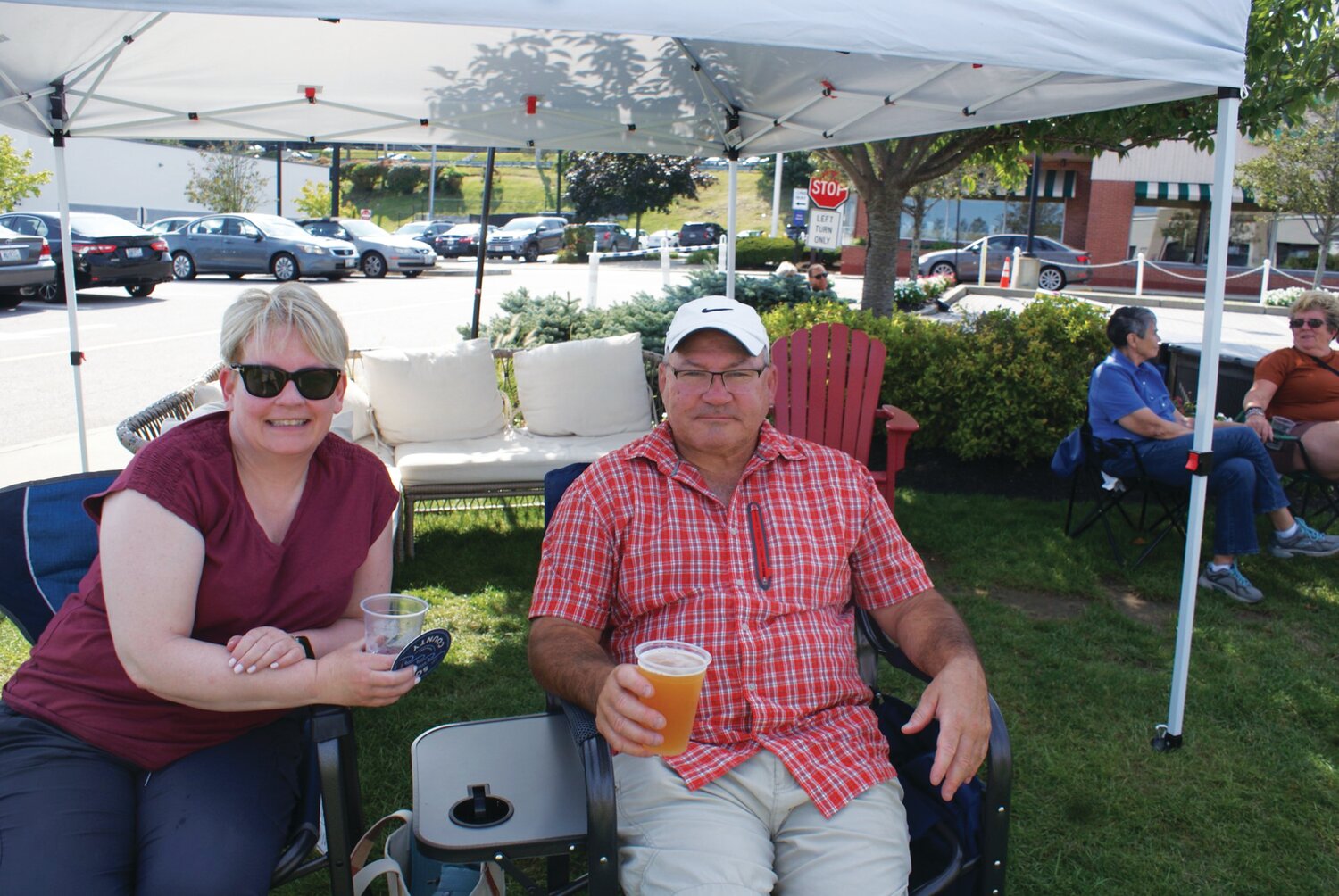 GREY SAIL SOLD: Lynn and Jon relax with some drinks and listen to music from a shady spot at the Garden City Beer Fest.