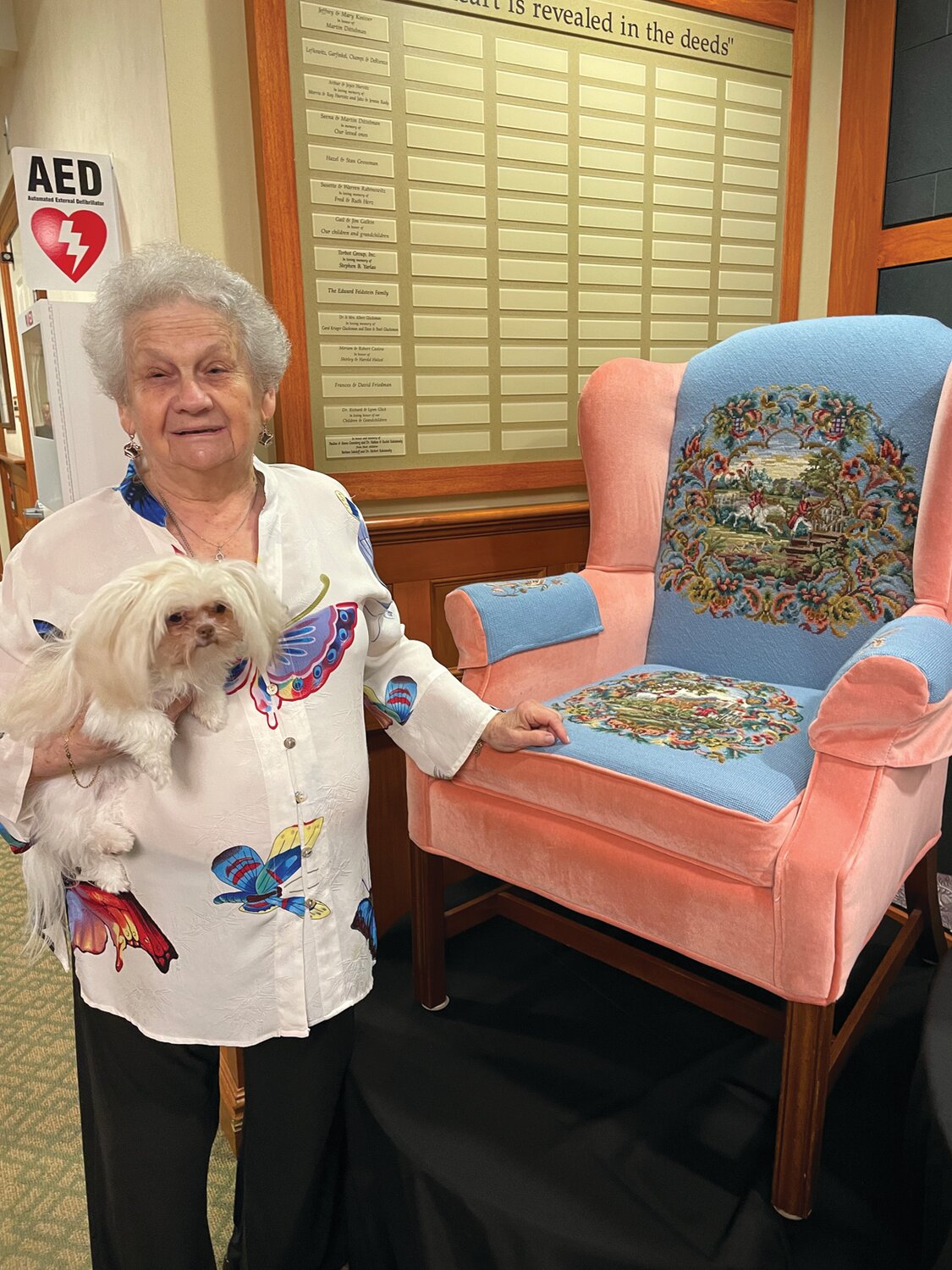 AMAZING HANDIWORK: Bertha, along with her trusty companion Melita, shows off the armchair she needlepointed. When asked how long it took, she said as long as it took.