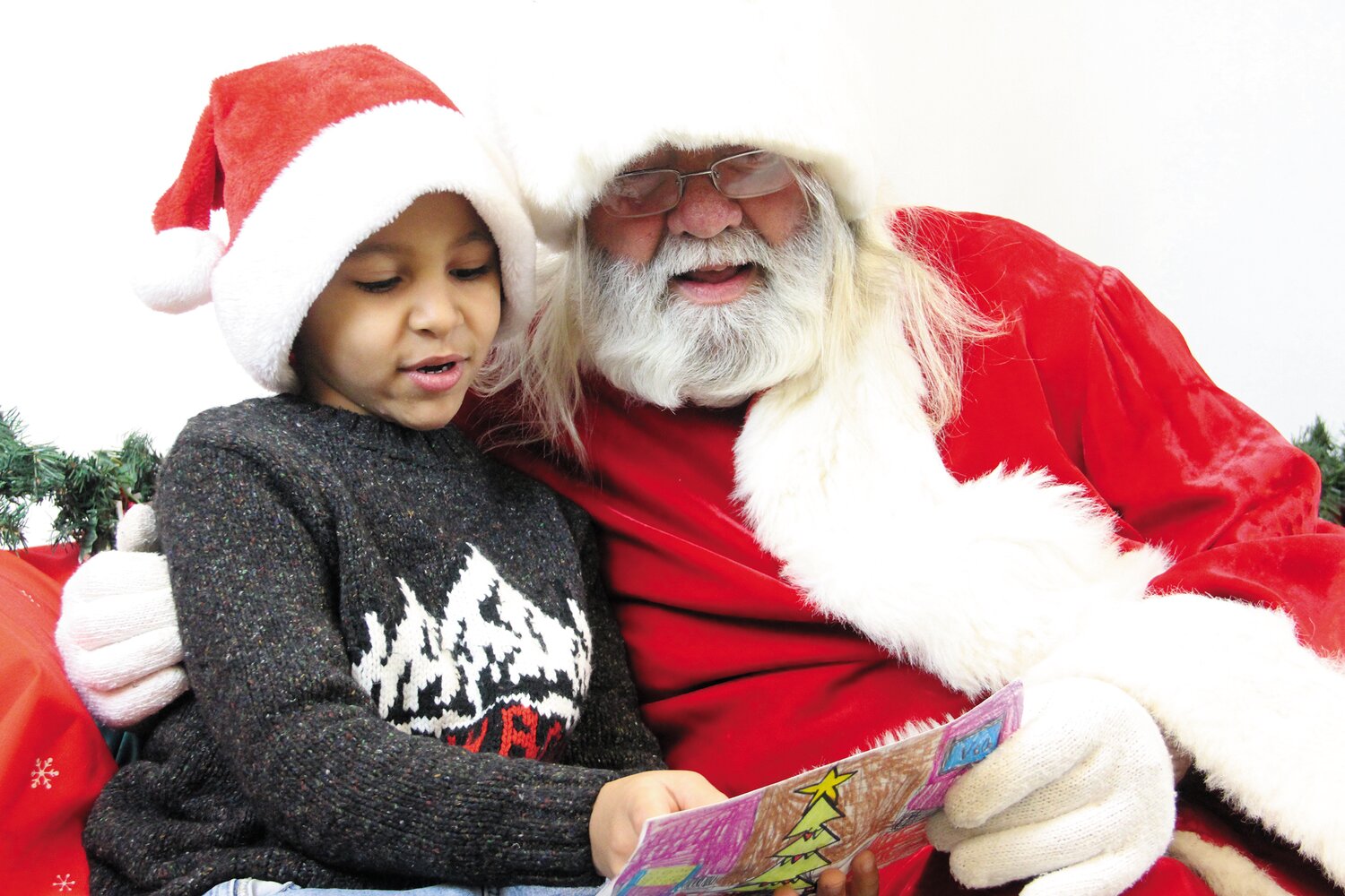 FIRST IN LINE: Makai Douthit brought a letter and a gift for Santa when he visited the Beacon last Saturday, And that’s Rep. David Bennett…and the beard is for real. (Warwick Beacon photo)